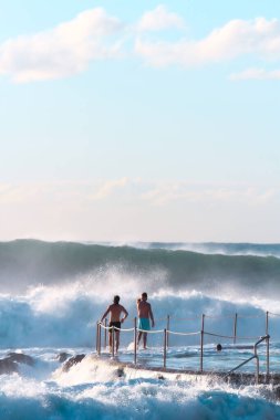 A beautiful view of men on a beach looking at big waves