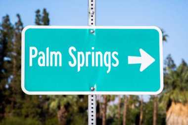A closeup of a direction sign with an arrow pointing to Palm Springs, California