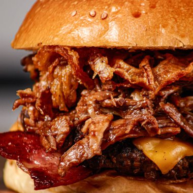 Arka planda bulanık bir şekilde izole edilmiş sulu bir hamburgerin yakın plan çekimi.