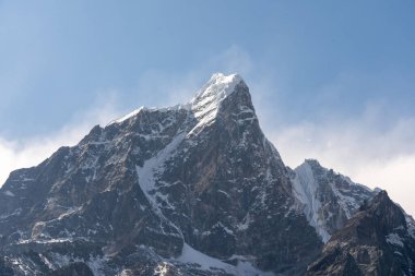 A snow-capped rocky mountain peak under a blue sky