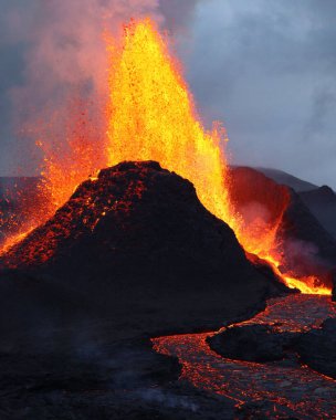 Yanan bir volkanın yakınında patlayan lavın dikey görüntüsü.