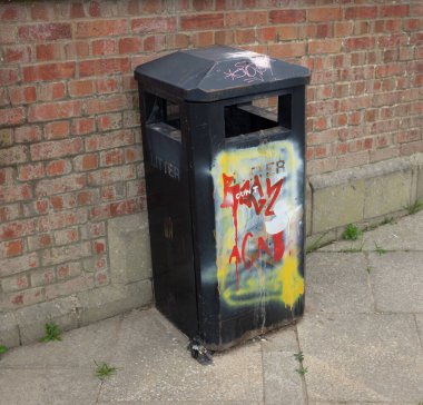 A closeup of a waste bin on pedestrian sidewalk with graffiti on it in Shrewsbury, England, United Kingdom