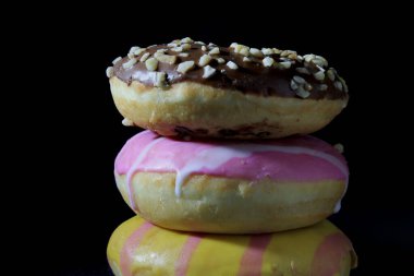 Koyu arkaplanda bir sütundaki çeşitli renkli çörekleri kapat