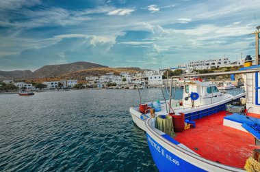 A beautiful boat in the sea in Karavostasi, Folegandros Island, Cyclades Greece with a blue cloudy sky