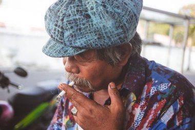 An old man with a classic hat and smoking cigarette in Yogyakarta, Indonesia