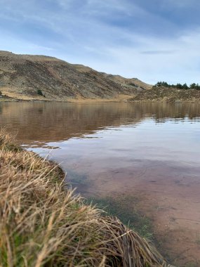 A natural view of a calm lake with the reflection of a mountain and sky on the surface
