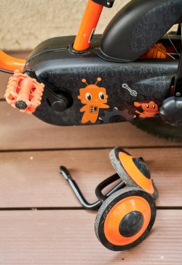 Bir çocuk bisikletinin yanında iki küçük destek tekerleğinin dikey çekimi.