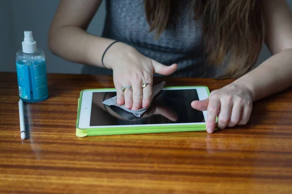 A close upwoman cleaning the screen of a tablet with special liquids