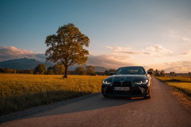 Günbatımında modern bir BMW M4 'ün, Dağ v. lüks spor arabalı görüntüsü birçok sürücünün hayalindeki arabadır.