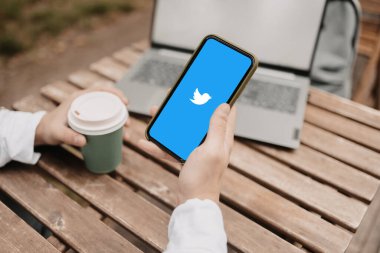 A hand with coffee and a phone with Twitter social network