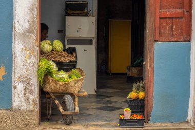 An elderly lady selling salads at the door of her house in Cuba