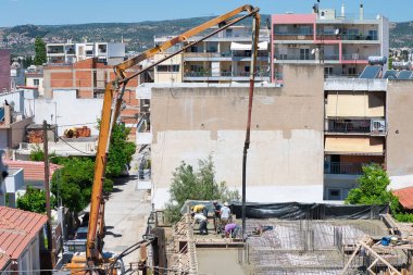 İnşaat işçileri, şehir merkezinde ev inşaatı. Beton ve beton döken özel bir tekerlek makinesinin yardımıyla. Volos Şehri, Yunanistan