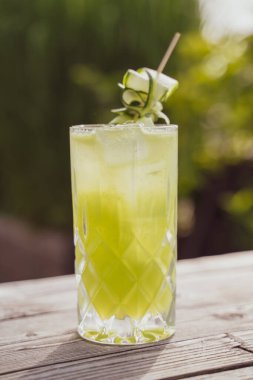 A vertical shot of a refreshing iced green tropical cocktail on the wooden surface