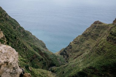 A gorgeous view of mountainous green hills overlooking the calm sea in Madeira, Portugal on a sunny summer day