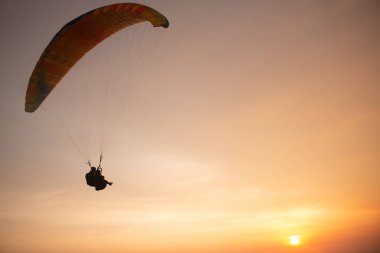Endonezya 'nın Java adasındaki Parangtritis plajında altın gün batımını izlerken okyanus üzerinde ikili paraşütle atlama
