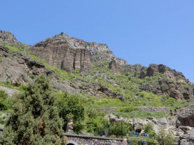 A scenic view of a rocky hillside with trees during summer in Armenia
