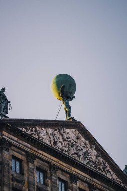 Amsterdam 'daki Kraliyet Sarayı' nın çatısındaki Atlas heykelinin alçak açılı bir görüntüsü.