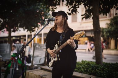 Gitar çalan ve sokaklarda şarkı söyleyen bir sokak müzisyeni.