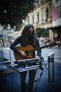 Gitar çalan ve sokaklarda şarkı söyleyen bir sokak müzisyeni.
