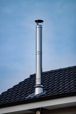 A vertical shot of a stainless steel chimney pipe on a roof