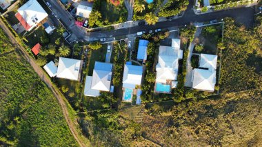 An aerial top view of multiple houses surrounded by trees and fields