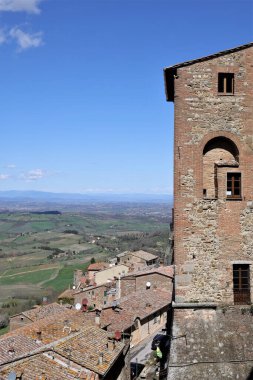 A vertical shot of the Abbey of Sant'Antimo Monastery in Italy tower against a blue cloudy sky on the horizon