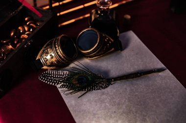 Eski Steampunk gözlükleri yanında boş bir kağıt üzerinde güzel bir tüy kaleminin yüksek açılı görüntüsü.