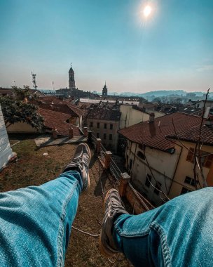 Çatıda oturan bir adamın dikey görüntüsü.