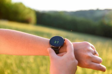 A selective focus shot of a person checking the time on a smartwatch outdoors