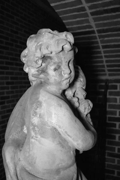 A vertical shot of an angel statue at night in a dark background