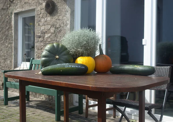 Farm shop outside entrance table with pumpkins Zucchini gas bottle converted as an oven with Halloween pumpkin face
