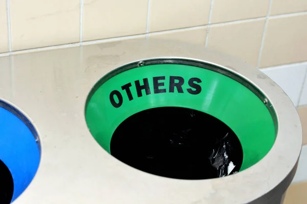 A closeup shot of the others\' wastes collection in a green color in a stainless steel metal trash bin for different garbage