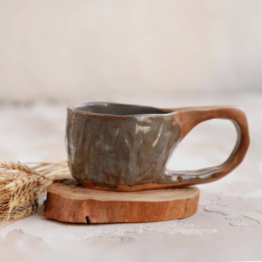 A closeup shot of an old ceramic mug with wheat on a wooden surface