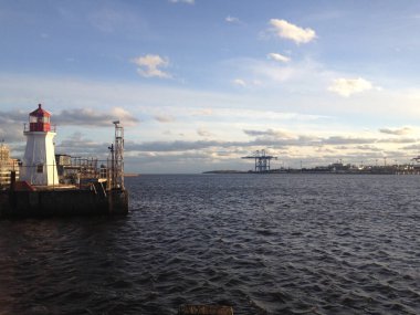 The Saint John Coast Guard Base Lighthouse in Saint John Harbor against a blue cloudy sky