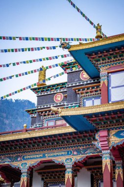 A vertical shot of the beautiful exterior of a Buddhist temple with prayer flags hanging above it