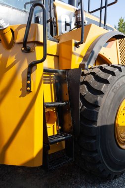 Güneşli havada büyük sarı bir buldozerin dikey görüntüsü.