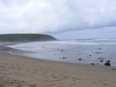 Kasvetli bir günde kumlu bir sahile vuran köpük dalgaları