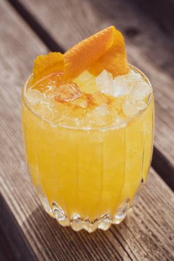 A vertical closeup shot of a cup of iced refreshing yellow tropical cocktail on the wooden surface