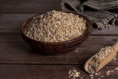 Tahta bir kasede, ahşap bir masa ve tuğla bir duvarda mutfak havlusuyla yulaf ezmesi.