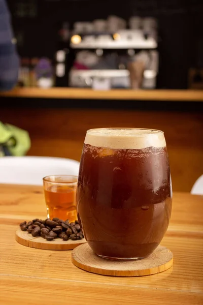 A vertical shot of a cold brew iced coffee and coffee beans on a table