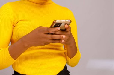 A woman in a yellow holding a smartphone