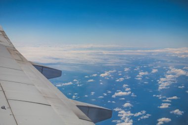 Mavi gökyüzü bulutlarına karşı yüksek irtifada uçan ticari uçağın kanadına bakın.
