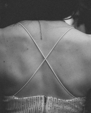 A grayscale of a woman's back in a beautiful dress