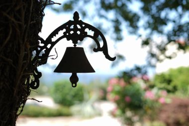 A silhouette of a hanging bell on a tree