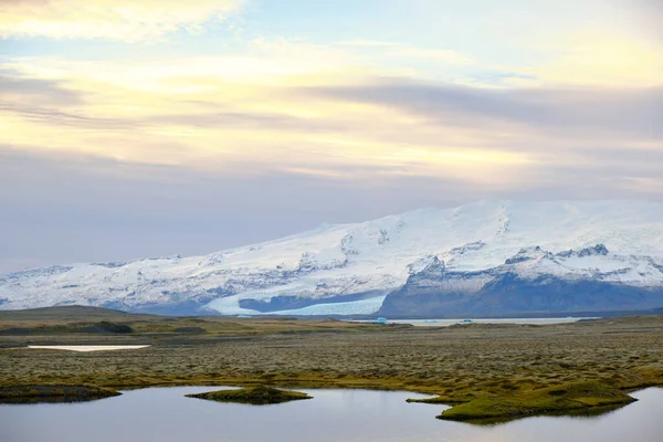 Snow covered mountain behind glacial melt lake