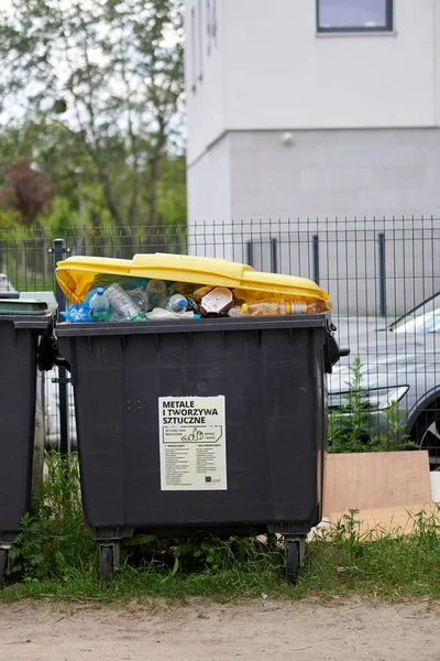 A vertical shot of a full trash container in the Stare Zegrze area, Poznan, Poland