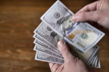 A top view of male hands holding dollar banknotes