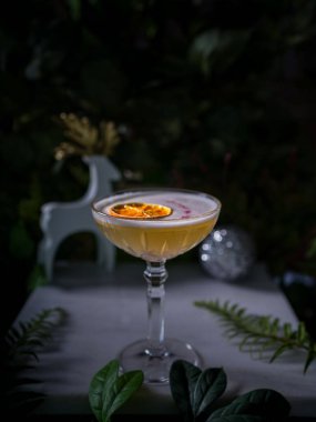 A vertical closeup of a glass of orange cocktail with lemon on the table