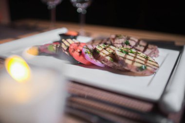 Kızarmış patates, domates ve soğanlı bir tabak et.