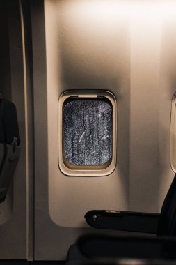 A vertical shot of a window of airplane from inside showing that it is snowing outside